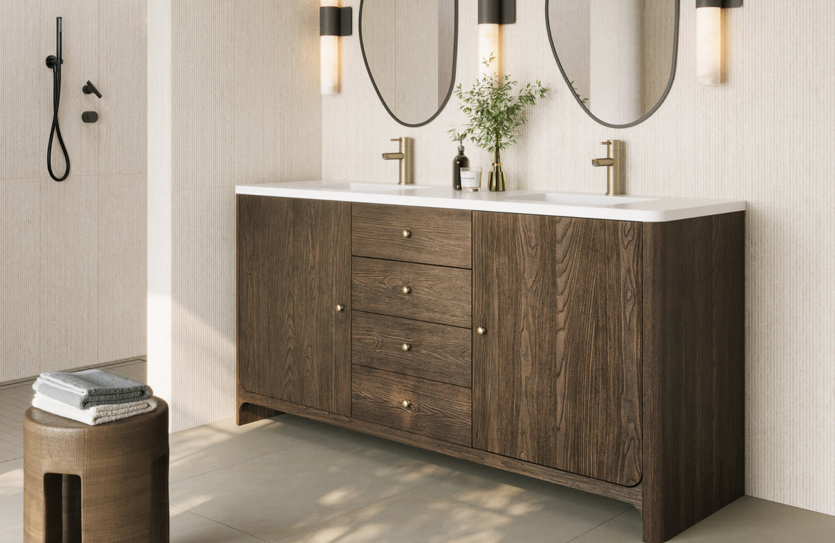Double sink vanity with dark wood cabinetry, brushed brass fixtures, and oval mirrors in a modern, minimalist bathroom with neutral finishes.