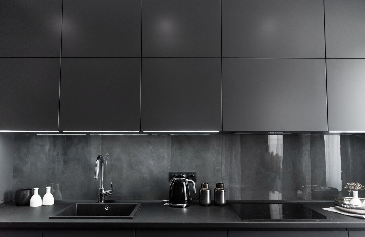 Modern kitchen backsplash featuring dark large format stone look tiles with minimal grout lines and sleek cabinetry for a seamless design.