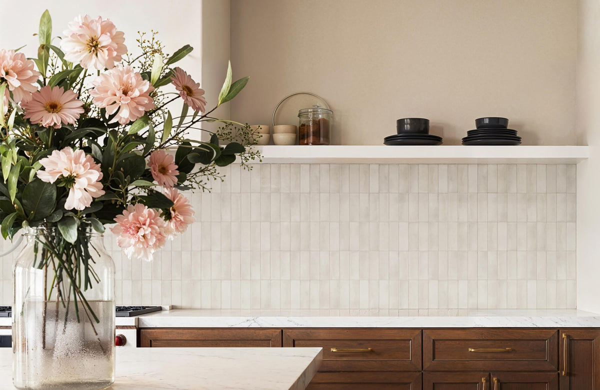 A warm, modern kitchen with a marble countertop and wood cabinetry, featuring a vertically stacked neutral subway tile backsplash that demonstrates how classic tiles can feel updated and on-trend.