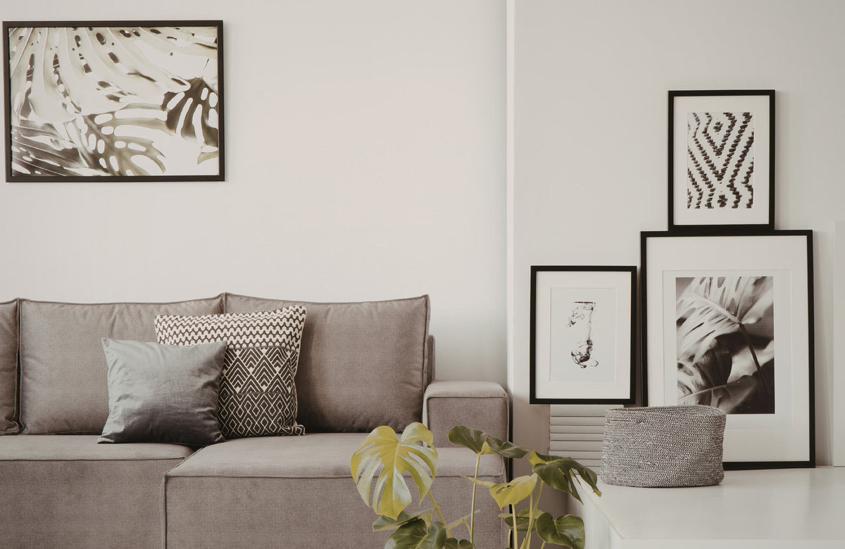 Neutral living room with beige sofa, textured pillows, black framed wall art, and layered botanical accents.