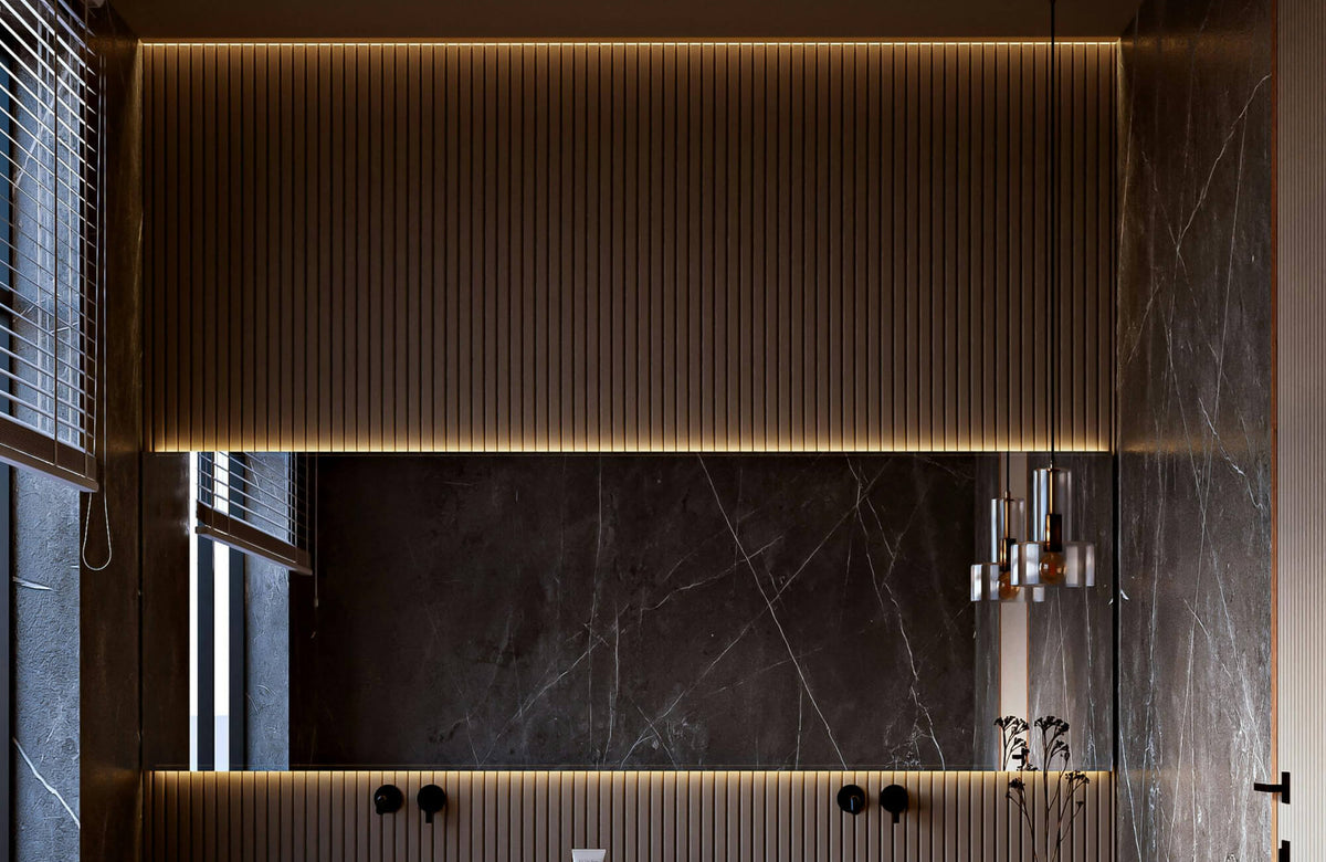Contemporary bathroom showcasing a large mirror framed by warm integrated bathroom light strips, accented by vertical wood slat detailing, dark marble wall panels, and a modern pendant fixture.