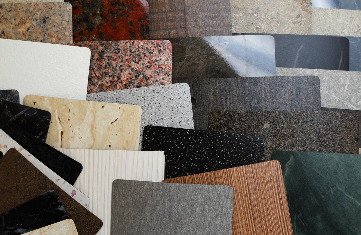 Assorted terrazzo, stone, and surface material samples layered together, showcasing varied colors, textures, and finishes for design selection.