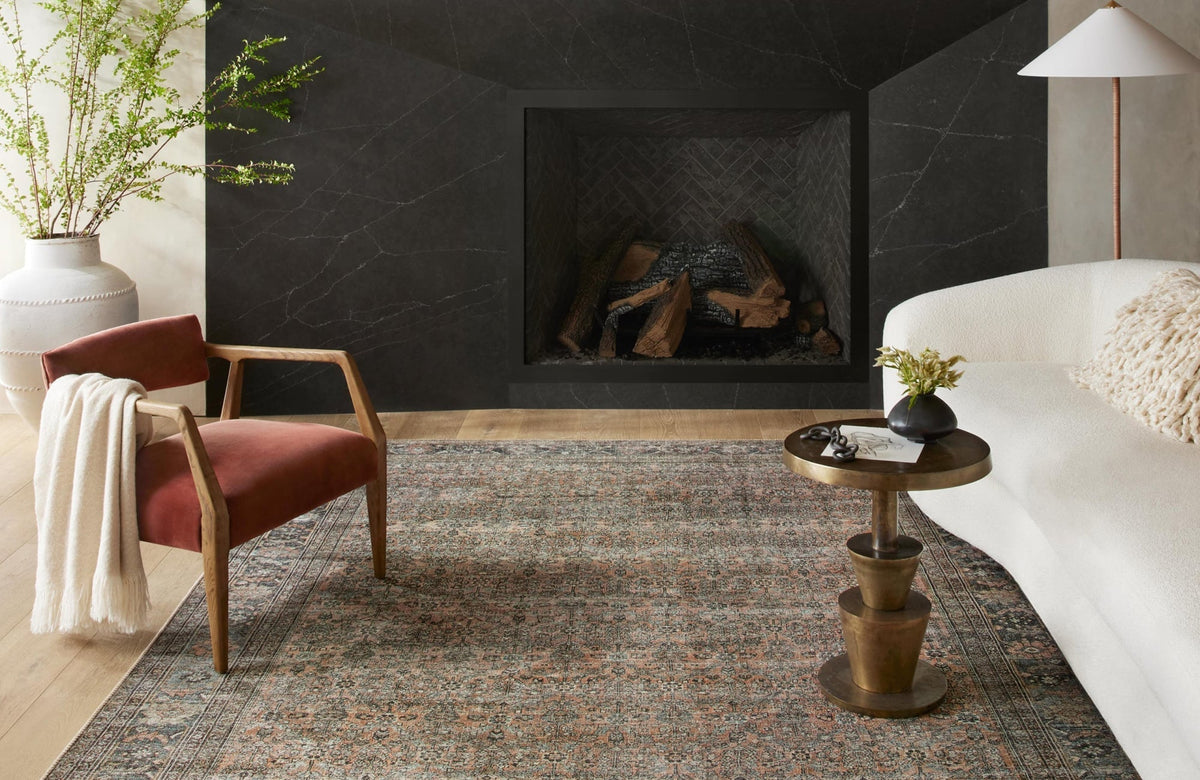 Elegant living room with a vintage-style rug, modern furniture, and a dark fireplace creating a cozy and sophisticated ambiance.