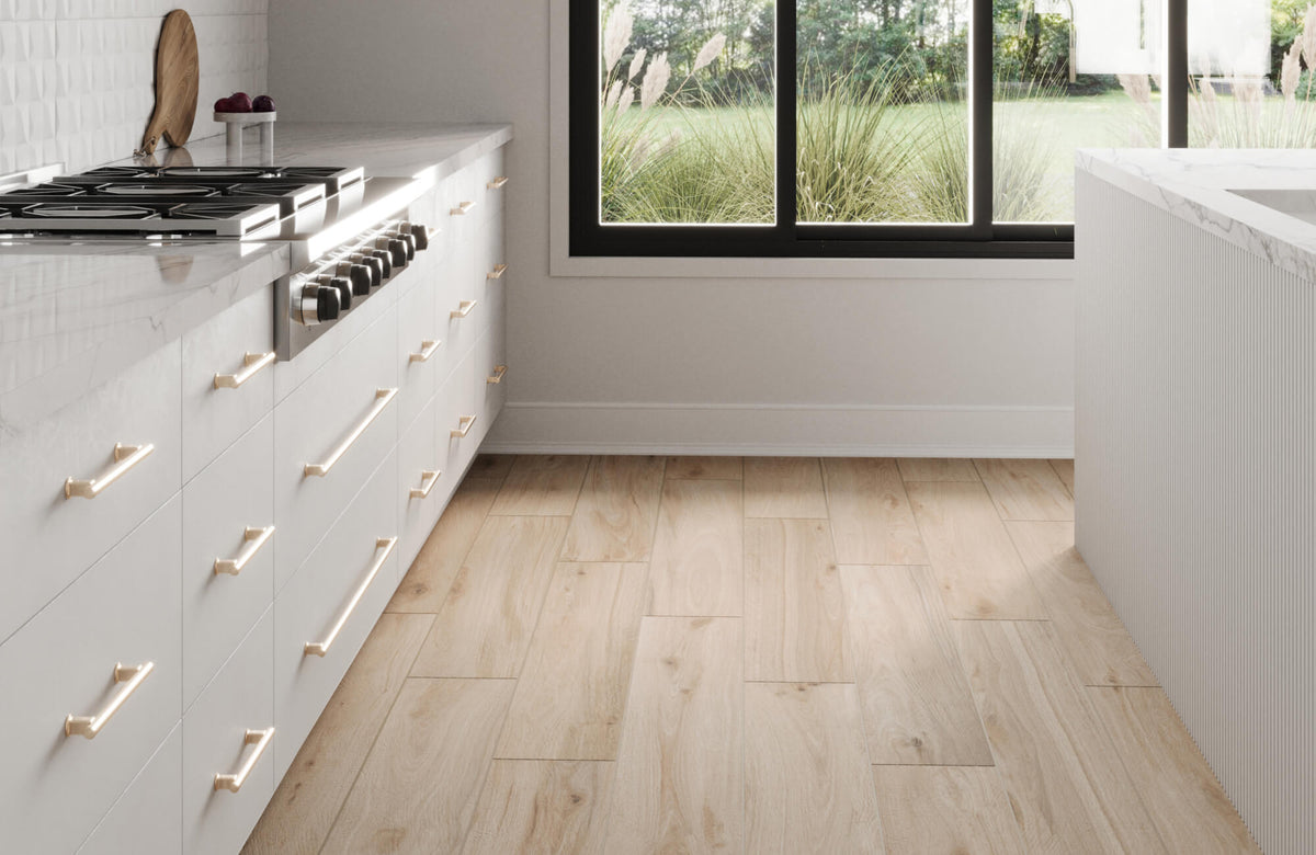 Sleek modern kitchen with birch wood look floor tiles laid in a staggered pattern near a large window and white cabinetry.