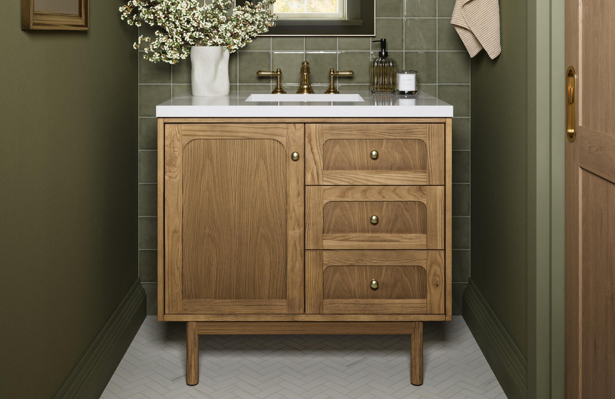 Mid-century modern bathroom vanity in natural wood with brass hardware, styled against olive green walls and square tile backsplash.