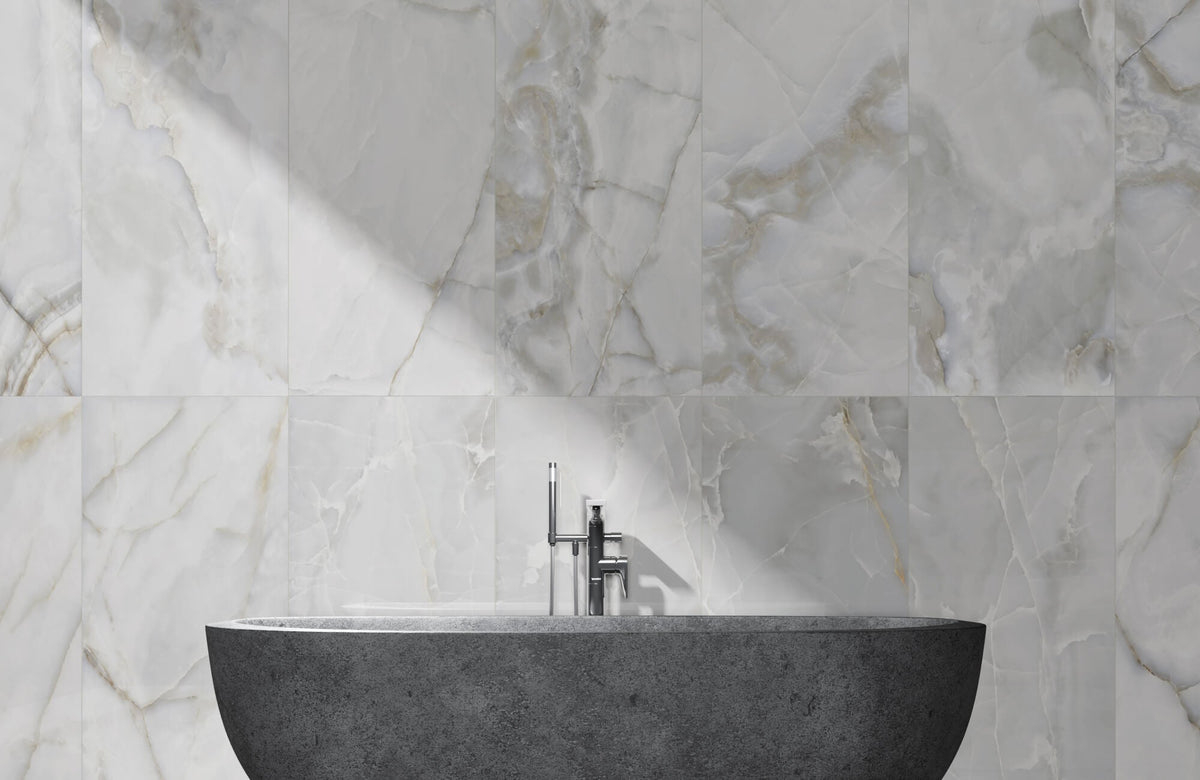 Elegant marble look wall tiles in a bathroom with a freestanding stone basin and soft natural lighting from above.