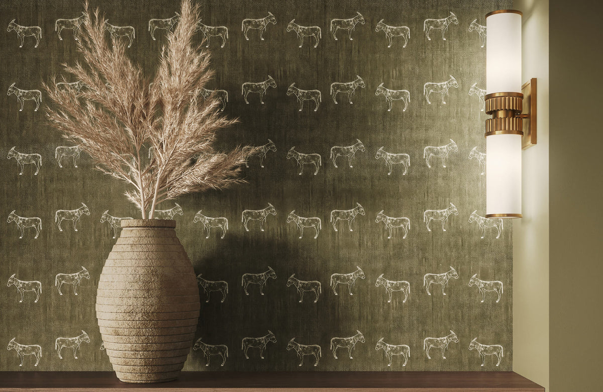 Olive green wallpaper with subtle animal motifs, styled with a textured vase, pampas grass, and a modern brass wall sconce.