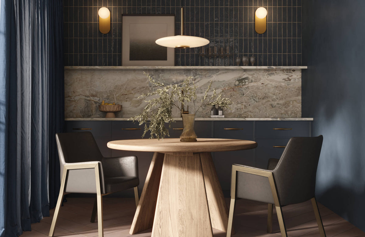Modern dining nook with a round wood table, leather chairs, a navy vertical subway tile wall, marble look backsplash, wall art, sconces, and pendant lighting.