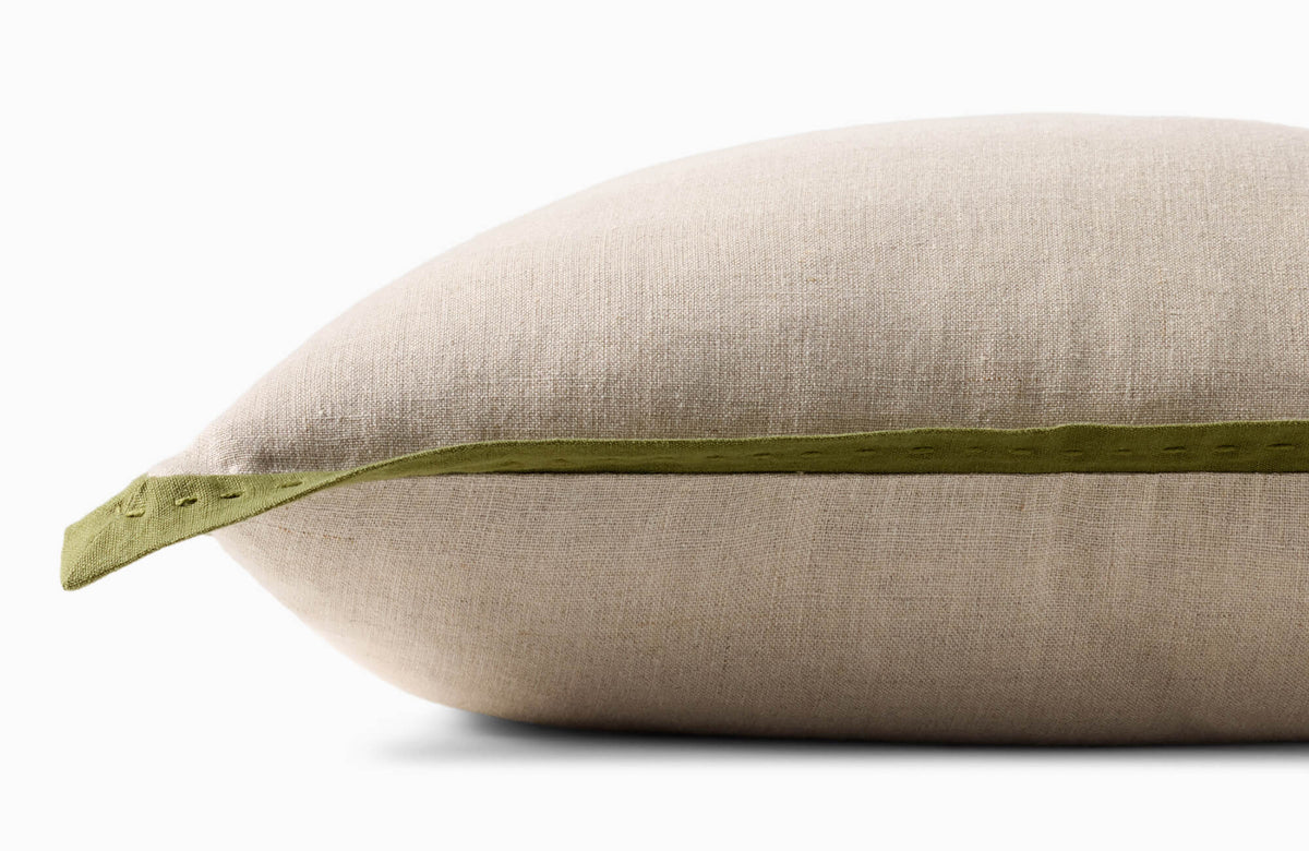 Close-up side view of a beige fabric pillow with a green stitched edge, showing the pillow’s loft, seam detail, and textured woven surface.