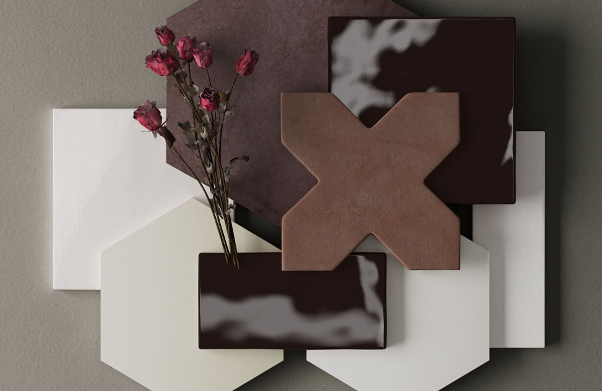 Flat lay of modern geometric tiles in earthy brown and cream tones with dried red flowers arranged on a neutral gray background.