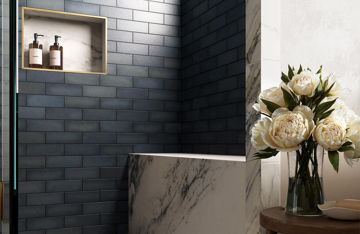 A luxurious bathroom featuring deep blue subway tiles, marble surfaces, and elegant brass accents, complemented by fresh ivory peonies.