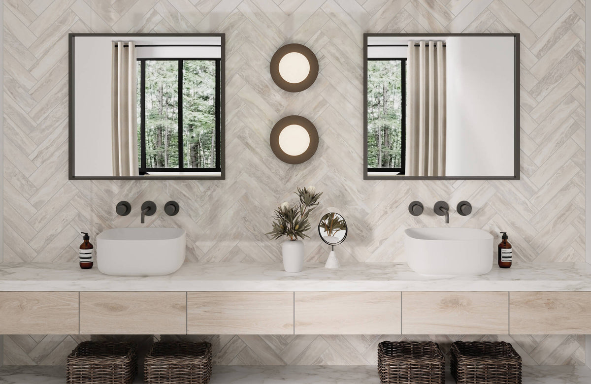 Elegant double vanity with a herringbone subway tile backsplash extending across the walls, marble countertop, modern vessel sinks, mirrors, and sconces, creating a serene, spa-like bathroom.