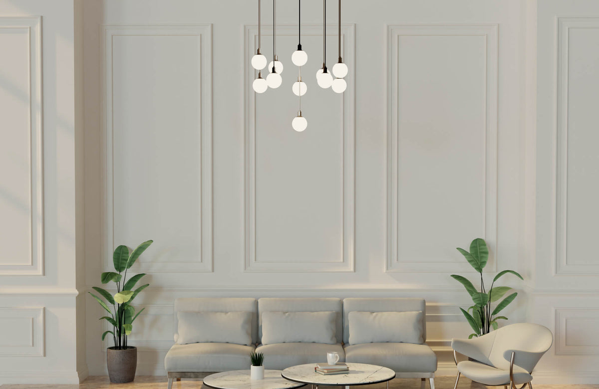 Elegant minimalist living room with soft globe pendant lighting, a neutral sofa, marble coffee tables, and lush potted plants adding natural balance.