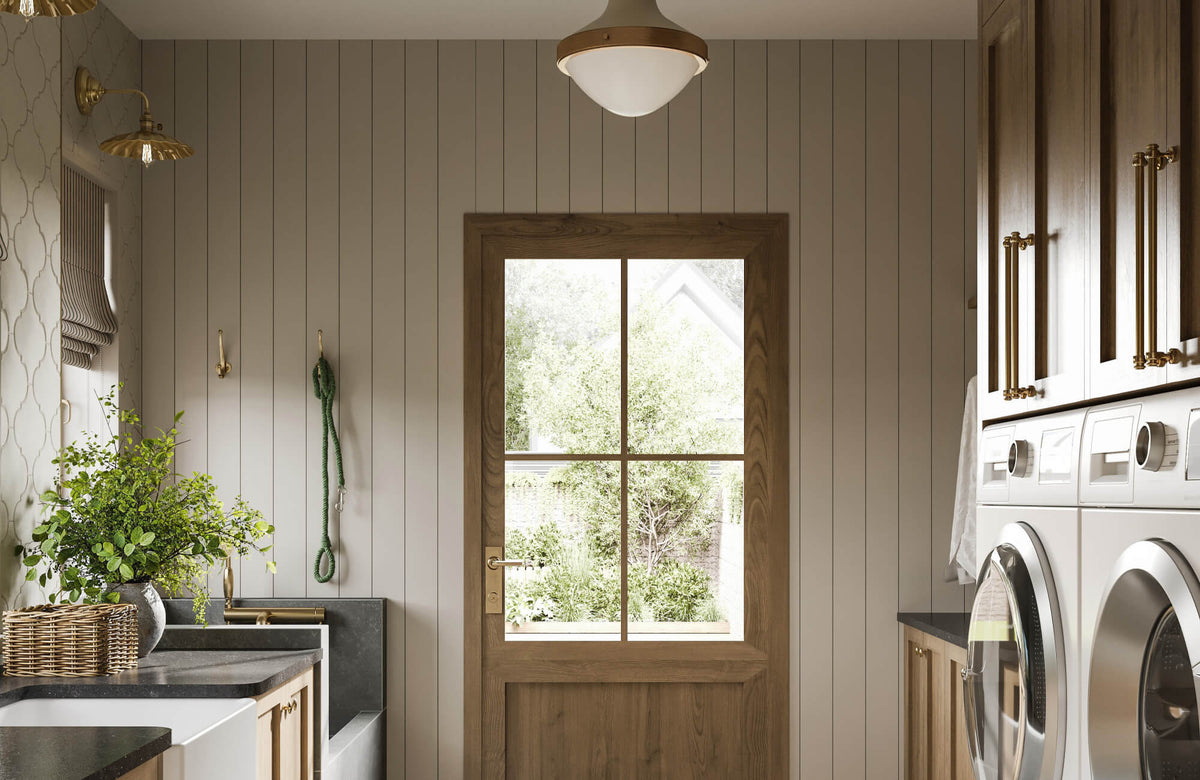 Bright laundry room with wood cabinetry, gold hardware, and a windowed door bringing in natural light for a warm, inviting look.