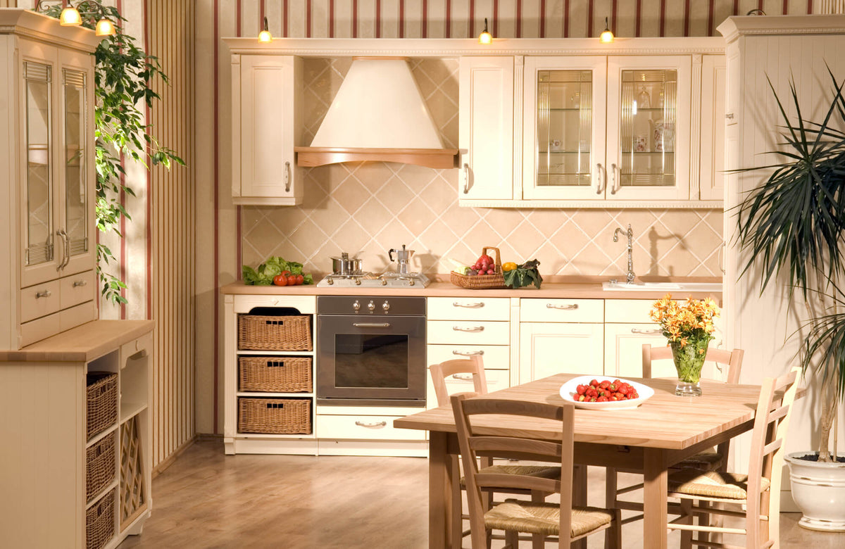 Bright, cozy kitchen with cream cabinets, wood countertops, wicker storage, and beige diagonal tile backsplash under warm lighting.