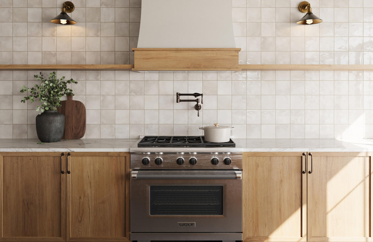 Modern kitchen with square ceramic tile backsplash, wood cabinetry, marble countertops, and stainless steel range under a wood-trimmed vent hood.