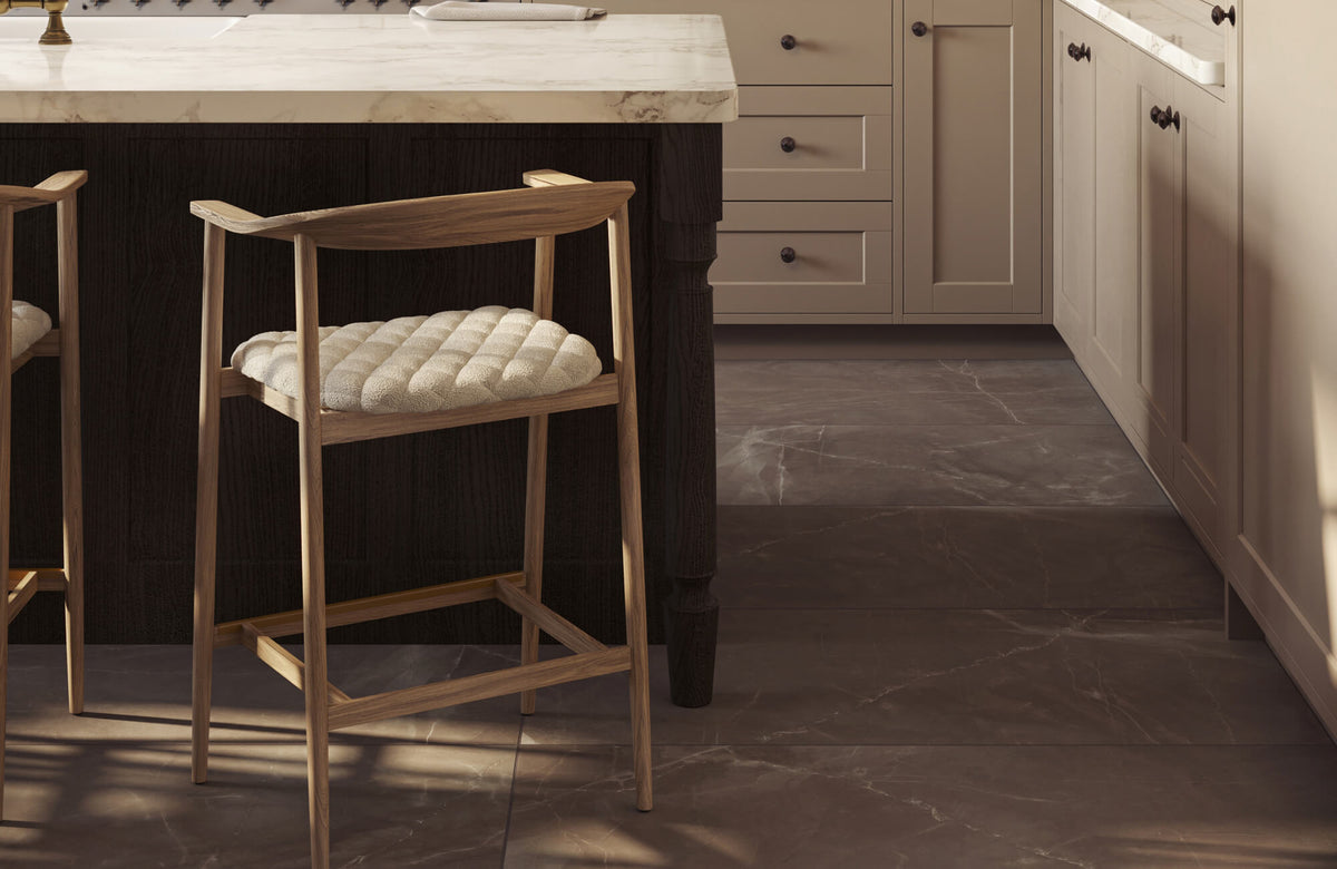 Kitchen interior with marble look tile flooring, featuring a wooden bar stool and a marble countertop island.