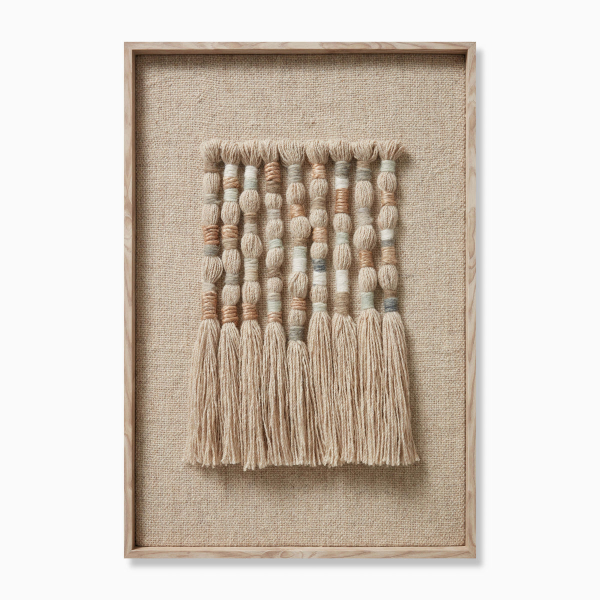 Framed textile wall art featuring hand-formed wool and jute knots arranged in vertical columns, with rounded, dimensional segments in soft earthy tones and long natural fringes that add movement and an organic, woven texture.