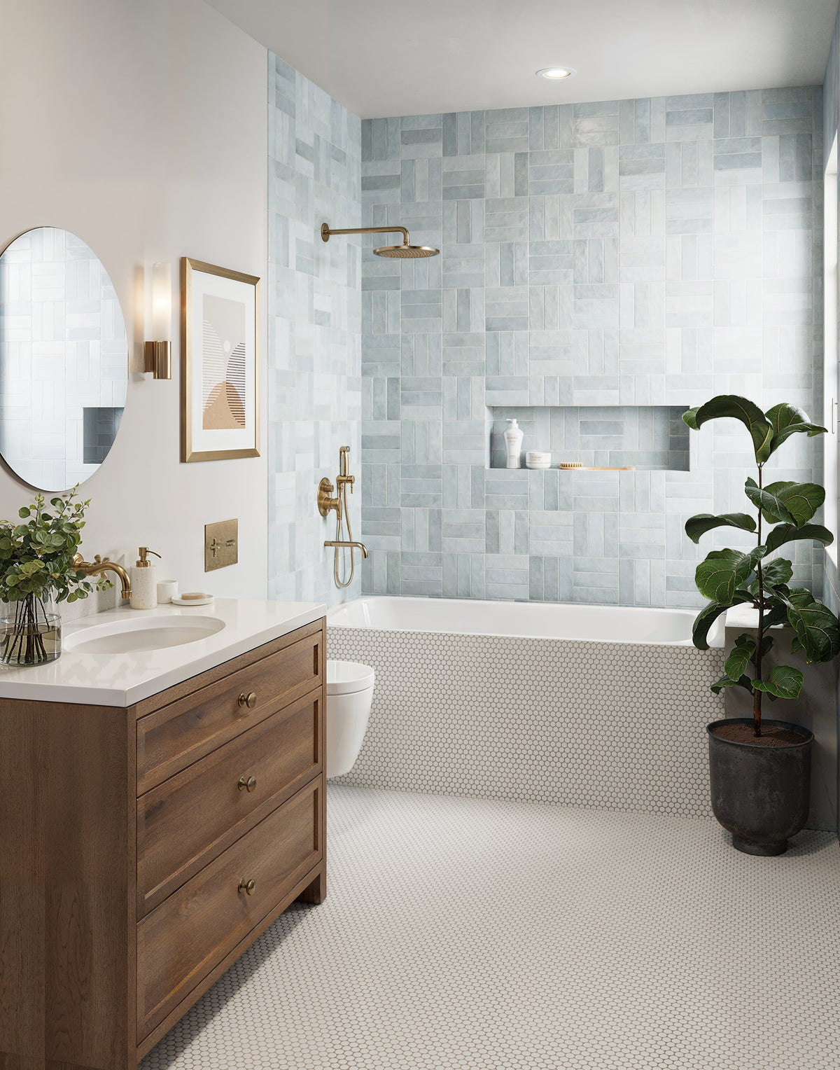 This bathroom showcases a serene design with blue wall tiles, brass fixtures, a sleek wood vanity, and a white hexagonal mosaic flooring for a harmonious blend of texture and warmth.
