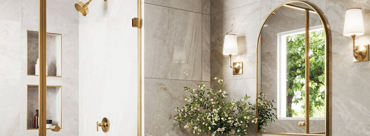 Luxurious bathroom with polished beige tiles, gold fixtures, and an arched mirror, accented by elegant built-in shelves and lush greenery.