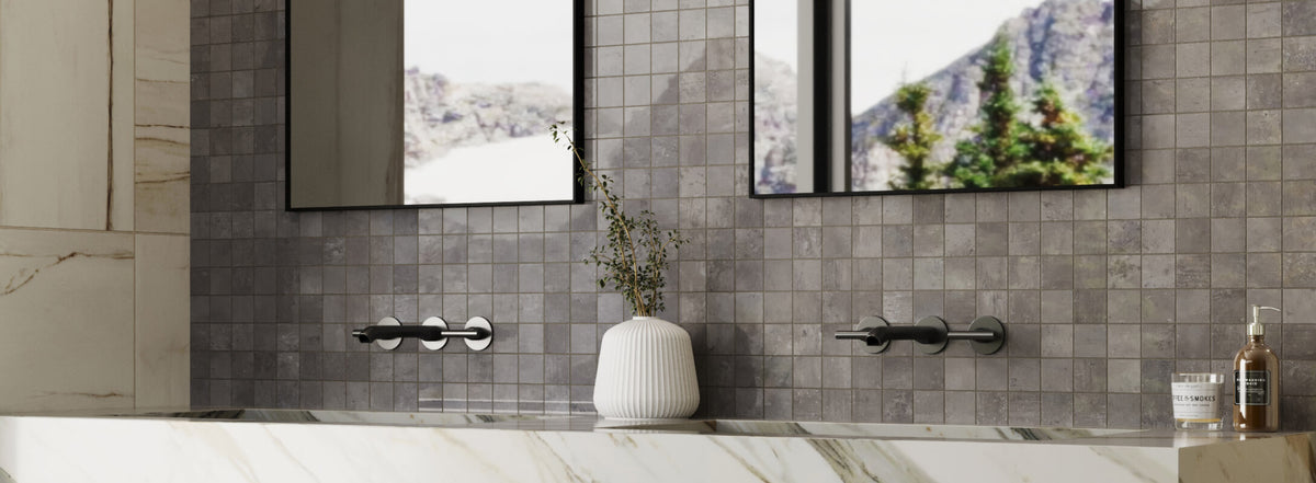 Textured mosaic tiles in muted greys behind a chic matte black faucet