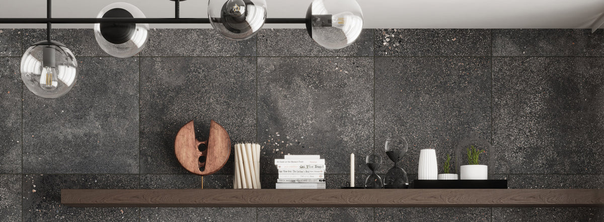 Modern interior featuring dark grey terrazzo-look tiles, with a floating wooden shelf adorned with decorative items and books, under stylish globe lighting