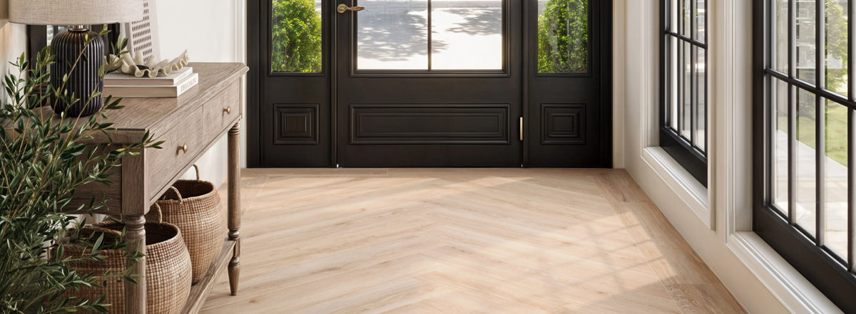 Bright and inviting entryway featuring porcelain floor planks that look like wood arranged in a herringbone pattern, a rustic wooden console, and large black-framed windows and doors