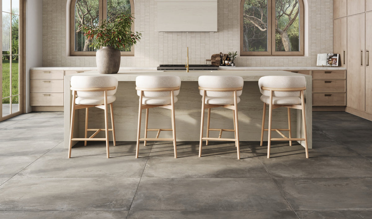Modern kitchen with large-format concrete-look floor tiles, paired with a neutral island and light wood stools, creating a sleek yet natural ambiance