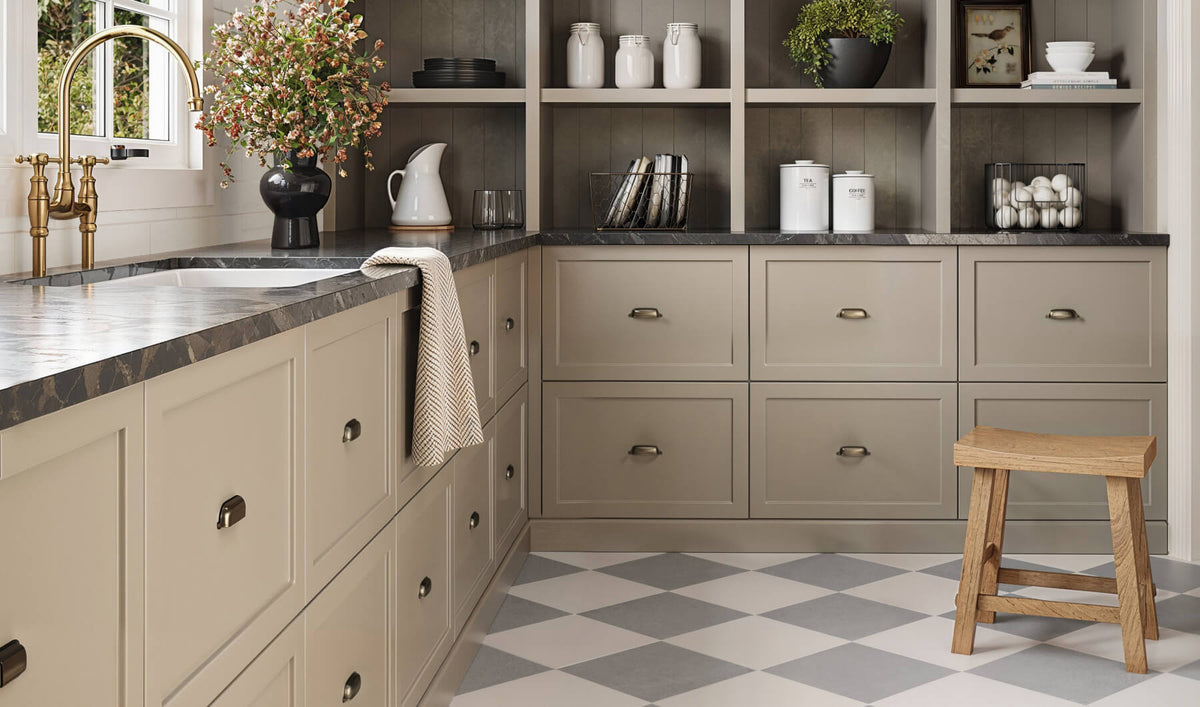 Charming kitchen with beige cabinetry, black marble countertops, and a 12x12 multicolor checkered tile floor in gray and white, creating a cozy and inviting space