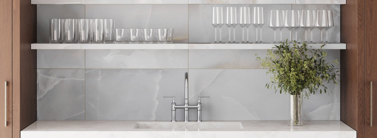 Elegant kitchen backsplash featuring 12x24 multicolor tiles in shades of gray and white, complemented by a modern chrome faucet and glassware
