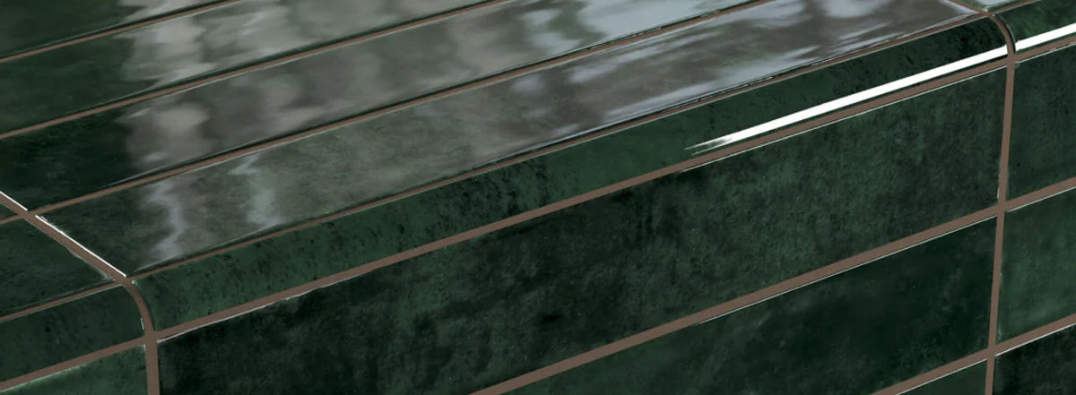 Close-up of a glossy deep green bullnose tile with a sleek finish and precise edges, reflecting natural light elegantly