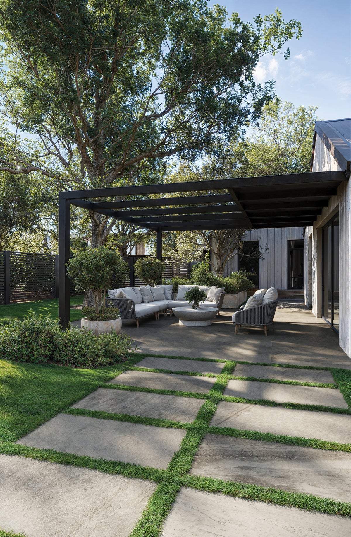 Outdoor patio featuring Carter Fossil 24x48 Matte Porcelain Pavers, 2cm thick, beautifully paired with lush greenery and modern seating arrangements.