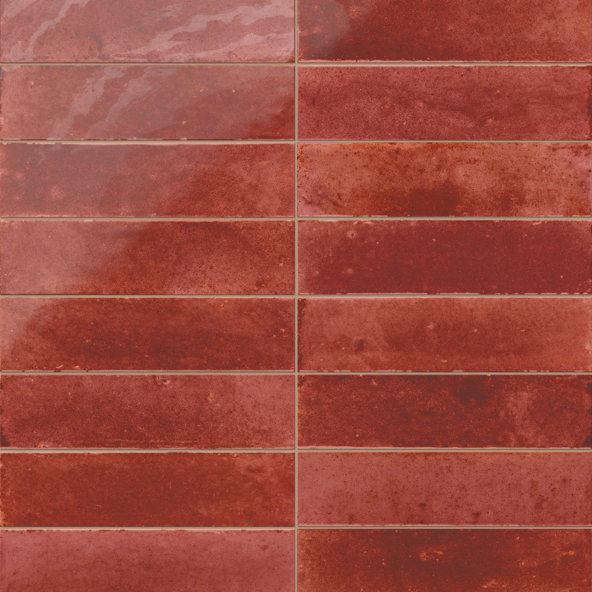 Glossy subway porcelain tiles in a rich brick red shade, featuring tonal shifts and a handcrafted look.
