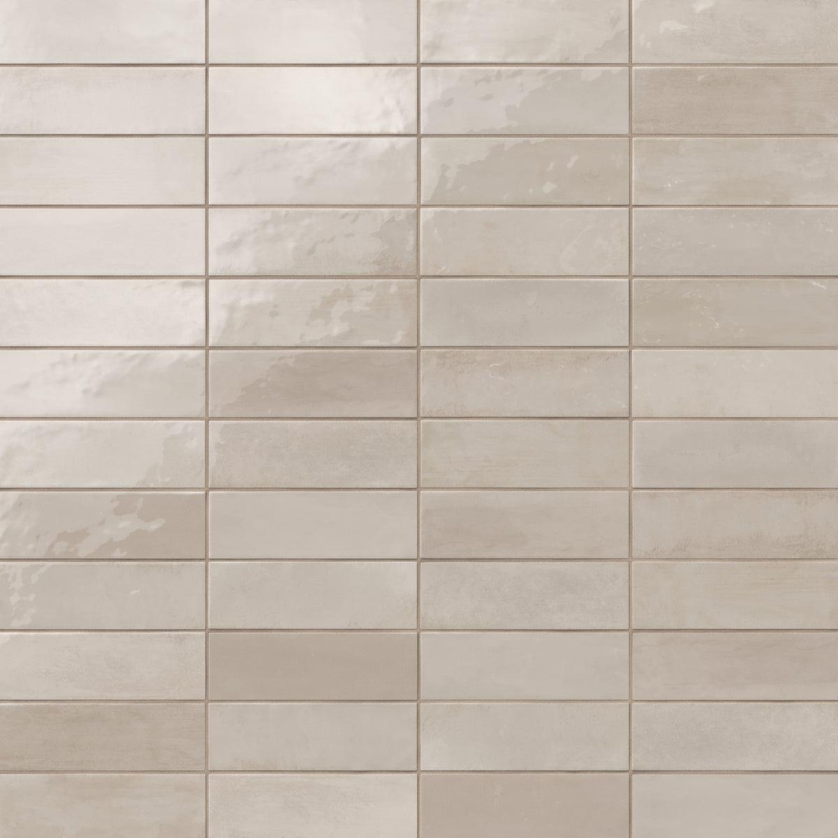 Glossy subway tiles in shifting grayish-beige tones with an artisan-like surface and subtle reflective finish