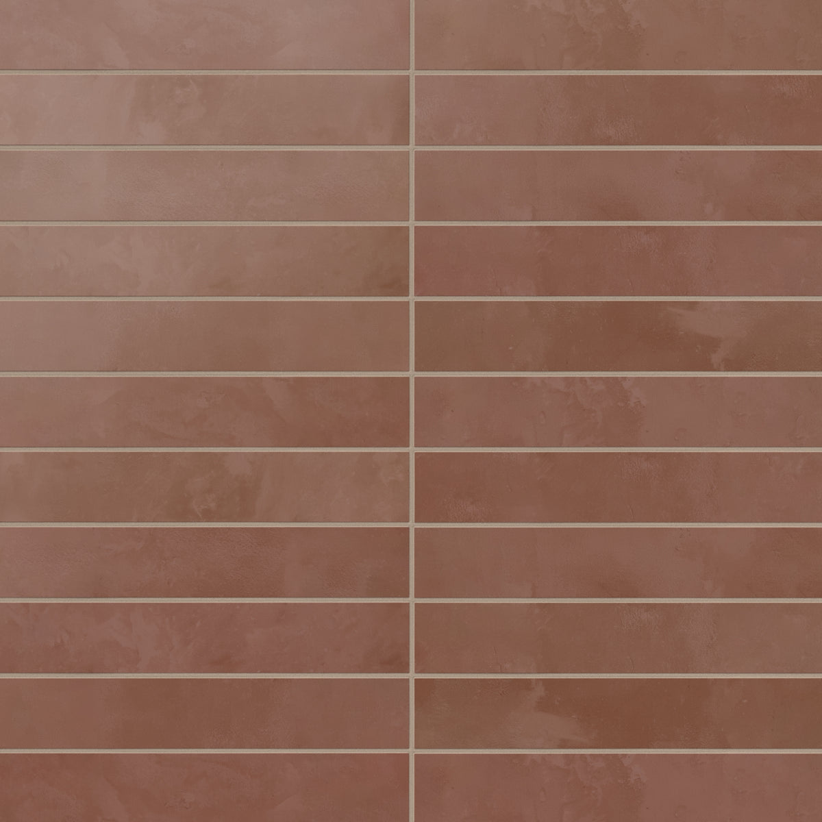 A run of 2.5x12 matte porcelain subway tiles reveals rich red shading with subtle surface variation, where earth-drawn tones and a powdery glaze soften the look.