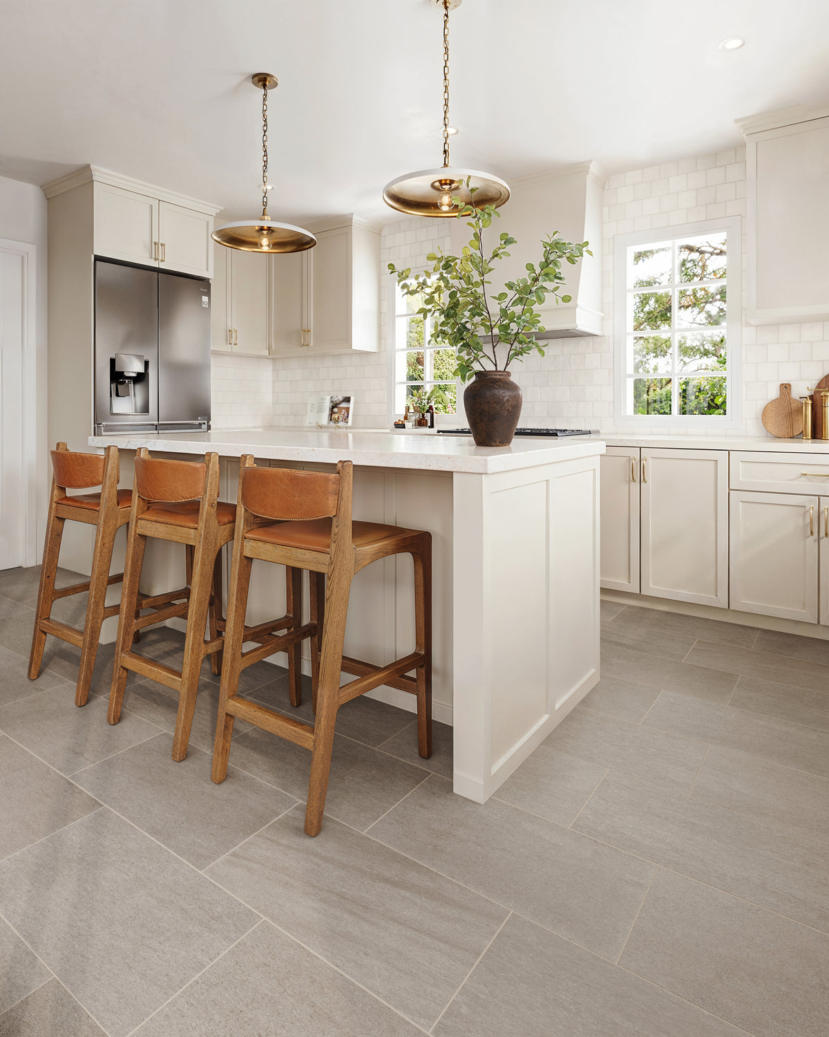 Modern kitchen design with white cabinets, brass pendant lights, and sleek porcelain tile flooring adding a sophisticated touch.