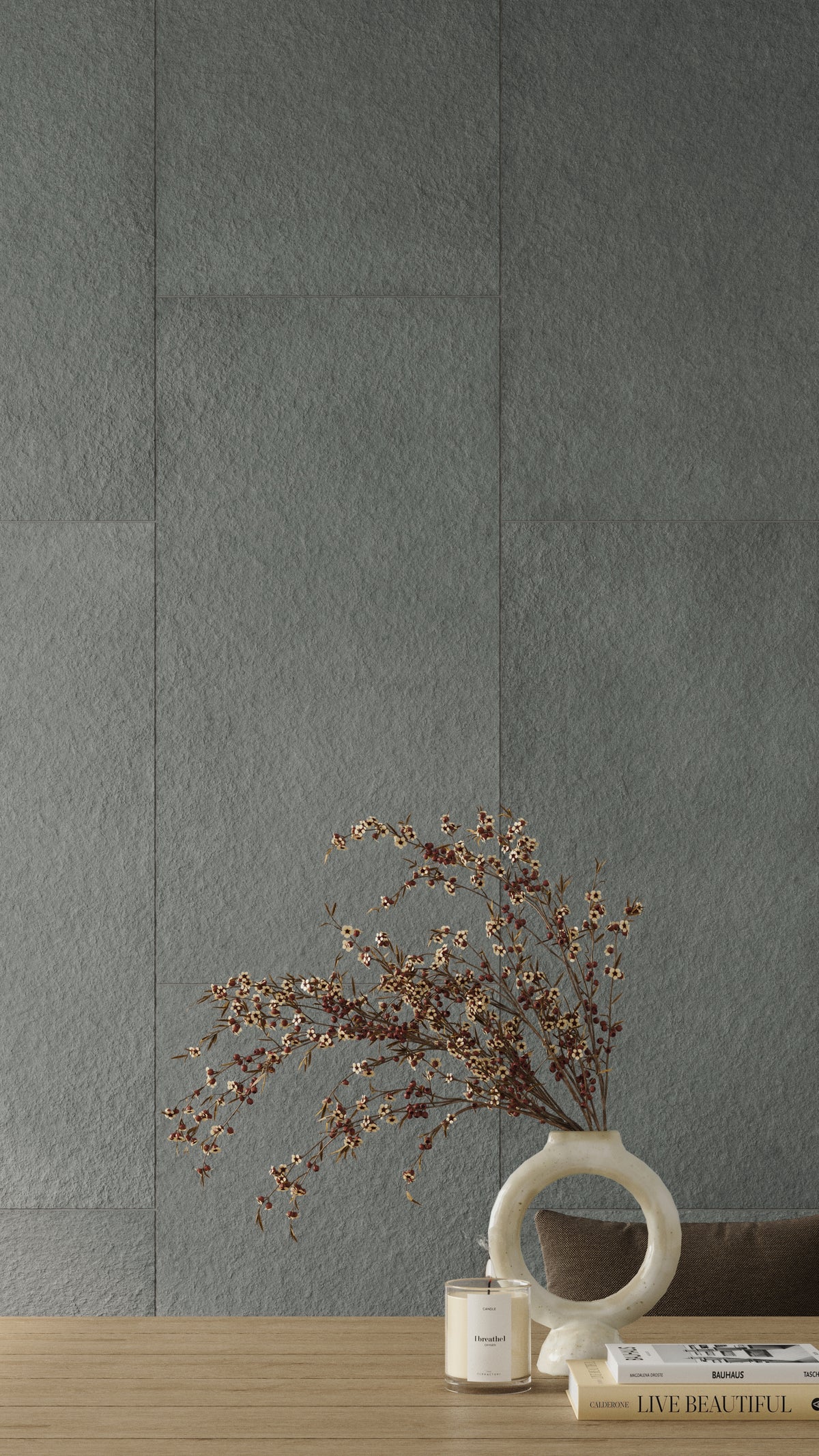A vase with dried flowers placed on a wooden table against a wall tiled with textured green-gray porcelain tiles, creating a natural and serene look.