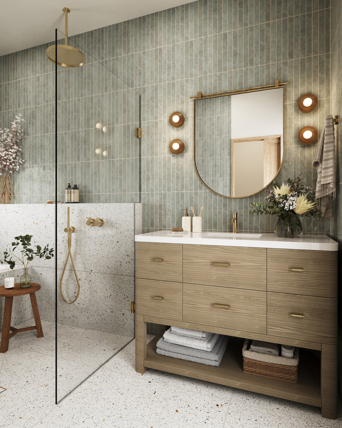 Pebble oak Paxton double vanity with brass hardware, arched mirror, terrazzo shower wall, glass panel, and vertical green tile bathroom.