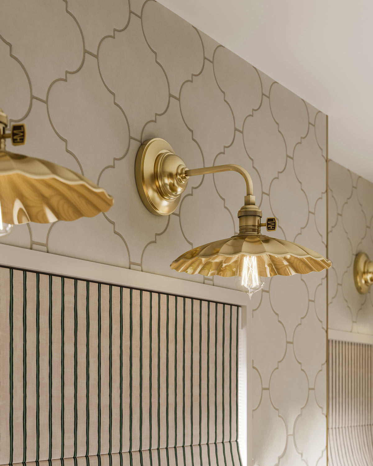 Close-up of a wall with Jasmine 8x8 white satin porcelain tile, featuring a lantern-inspired arabesque pattern. The smooth satin sheen adds softness and elegance beneath sculpted brass wall sconces.