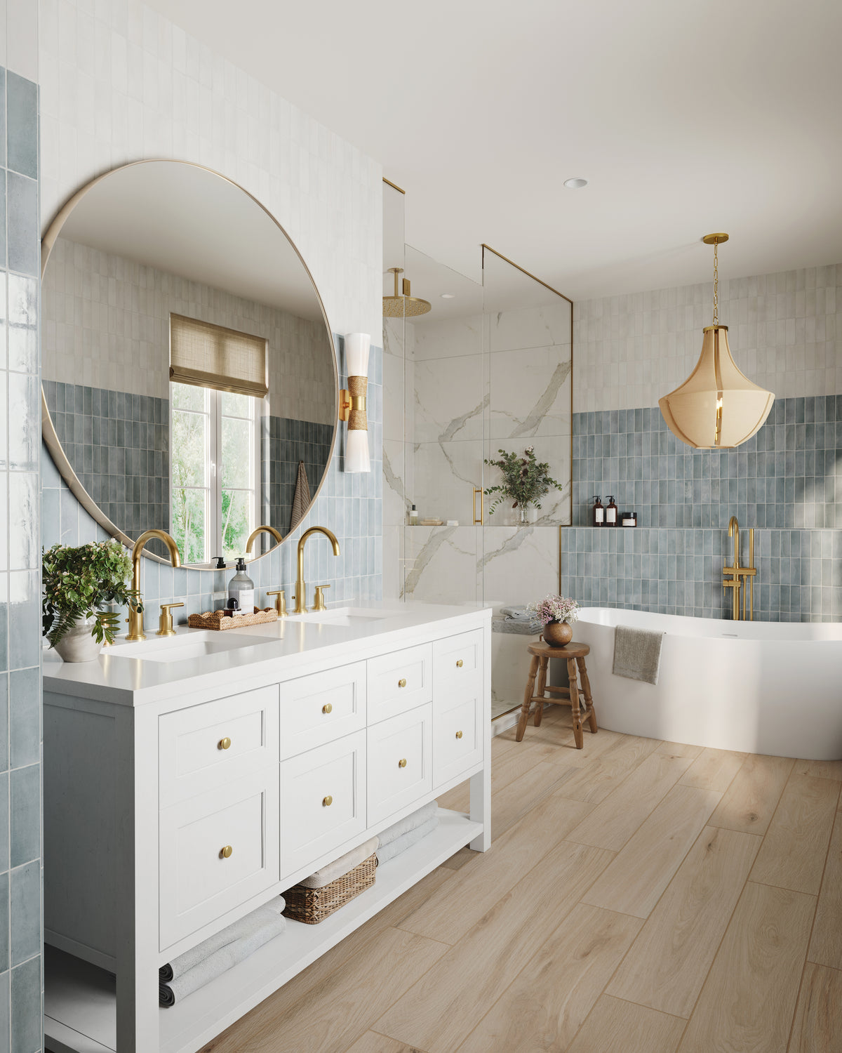 Bright spa-like bathroom with a white double vanity, white quartz countertop, and brushed gold faucets beneath a large round mirror and sconces. Light blue wall tiles wrap the space, leading to a freestanding tub, glass shower with marble walls, warm wood flooring, and a pendant light above the bathing area.