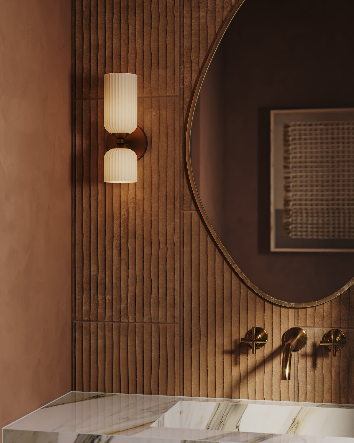Brushed gold wall light with vertically stacked ribbed glass shades illuminating wood slat wall panels beside a round mirror above a marble sink.
