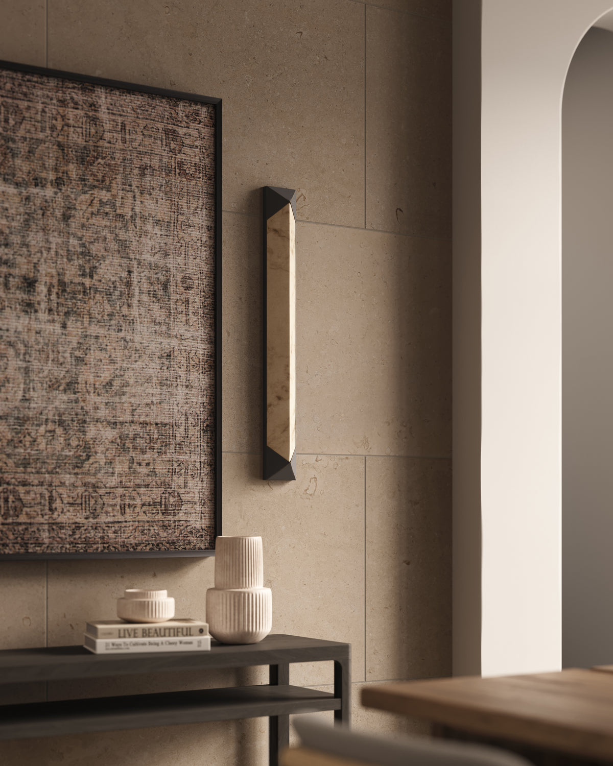 Modern LED wall sconce with alabaster-style diffuser and dark geometric metal caps mounted on a textured stone look tile wall beside a wall art.