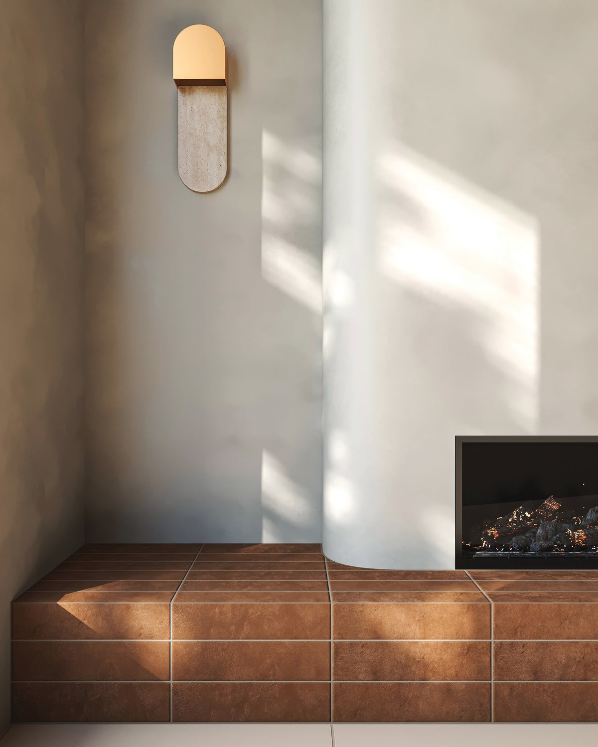 Modern interior fireplace hearth clad in rectangularporcelain tiles with a matte finish and smooth, lightly textured surface in a warm reddish brown color, paired with a curved light off-white wall, a minimalist wall sconce, and soft natural light casting shadows.