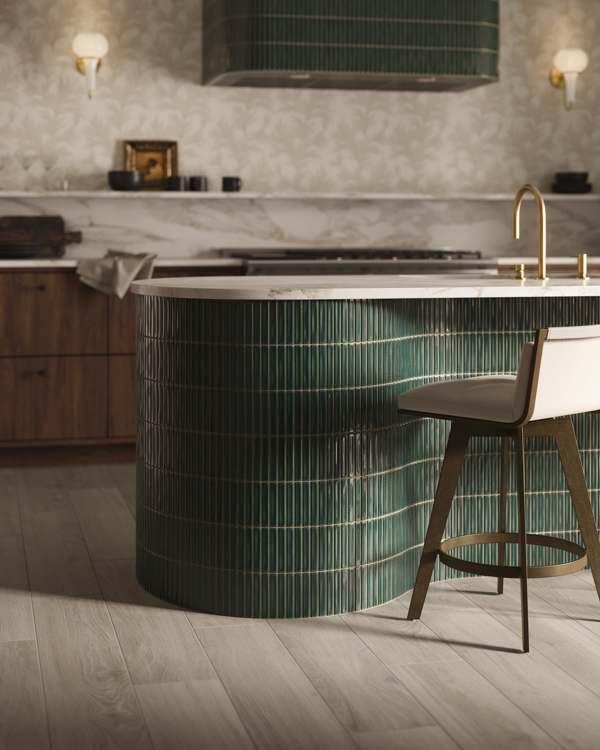 Modern kitchen with a curved island wrapped in glossy dark green kitkat mosaic-look tile, topped with a white stone countertop and brass faucet, with a bar stool, wood cabinetry, marble backsplash, patterned wallpaper, and wall sconces in the background.