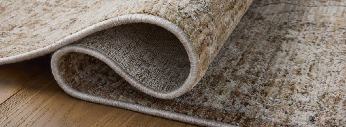 Close-up of a traditional rug with soft beige and earthy tones, showcasing intricate patterns and durable stitched edges