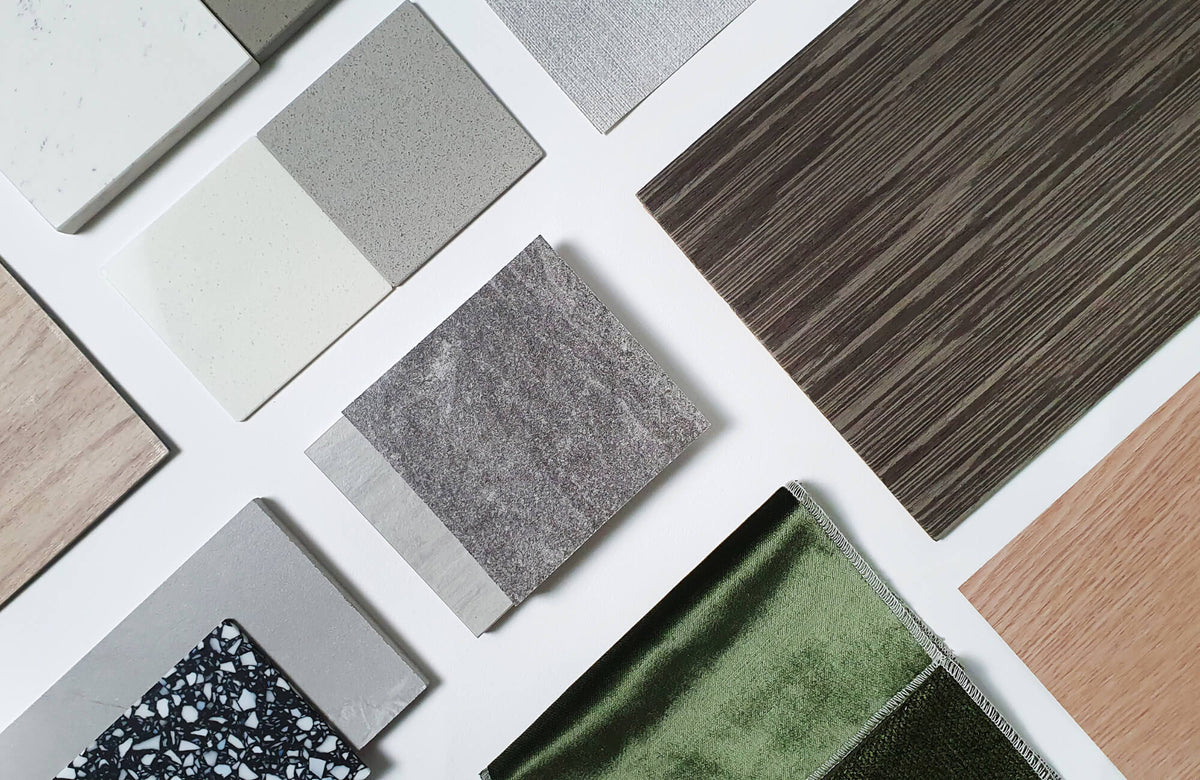 Flat lay of terrazzo, stone look tiles, wood, and fabric samples arranged on a white surface, highlighting texture, color, and finish options.
