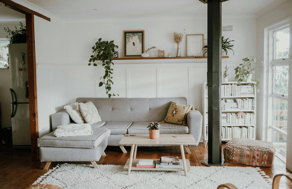 Scandinavian living room with a light gray sectional sofa, natural wood flooring, and soft neutral accents that create a calm, airy atmosphere.