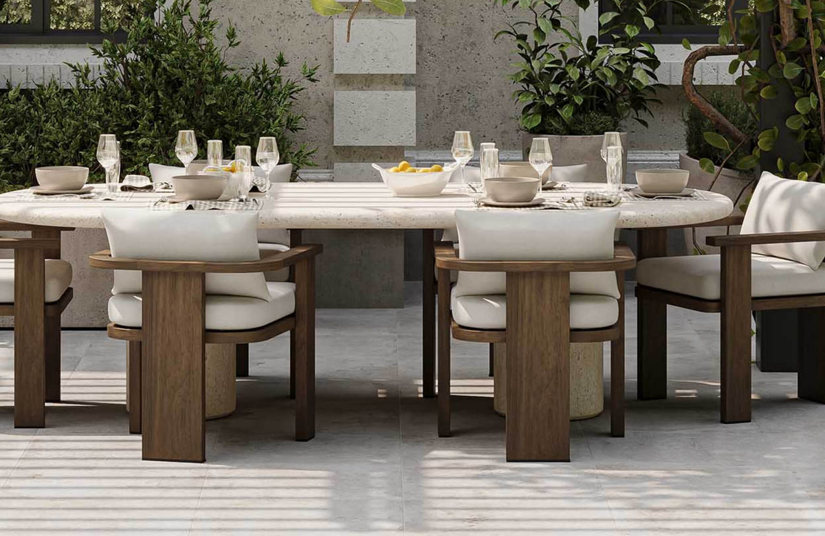 Comfortable outdoor dining chair with plush white cushions and a solid wood frame, arranged around a spacious patio table in a modern garden setting.