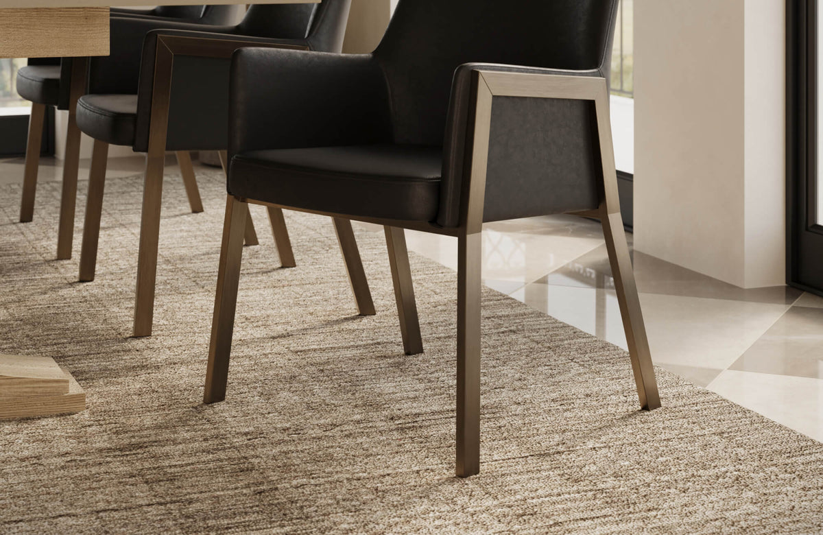 Neutral-toned textured rug anchors the dining area beneath sleek black chairs and a wooden table, adding warmth, subtle pattern, and refined comfort to the modern interior.