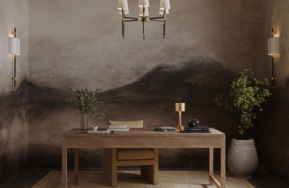 Moody home office featuring a painterly mountain mural wallpaper with walnut shelving, brass lighting, and warm decor accents.